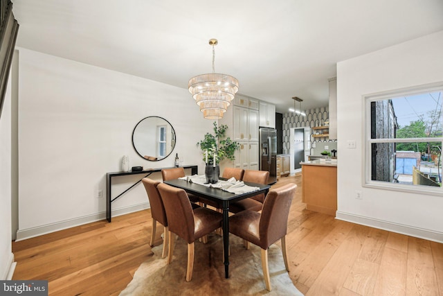 dining space with a chandelier, light wood finished floors, and baseboards