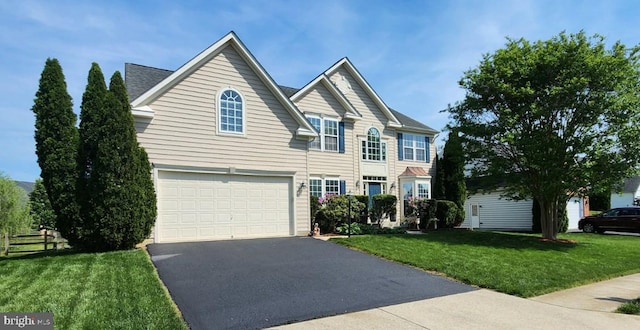 view of front of home featuring an attached garage, a front lawn, and driveway