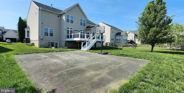 rear view of house featuring fence, a residential view, a wooden deck, stairway, and a lawn