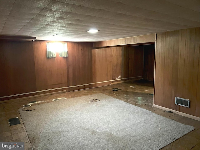 finished below grade area featuring wooden walls and visible vents