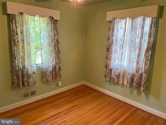 empty room with visible vents, baseboards, and wood finished floors