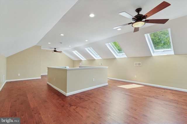 additional living space with ceiling fan, wood finished floors, baseboards, lofted ceiling with skylight, and recessed lighting