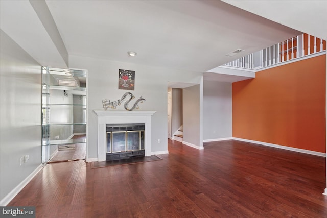 unfurnished living room featuring visible vents, wood finished floors, baseboards, stairway, and a fireplace with flush hearth