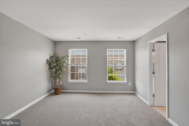spare room with baseboards, visible vents, and carpet
