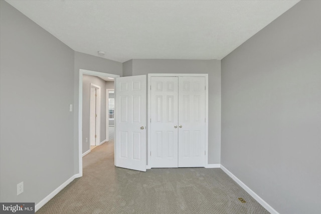 unfurnished bedroom featuring baseboards, carpet, and a closet