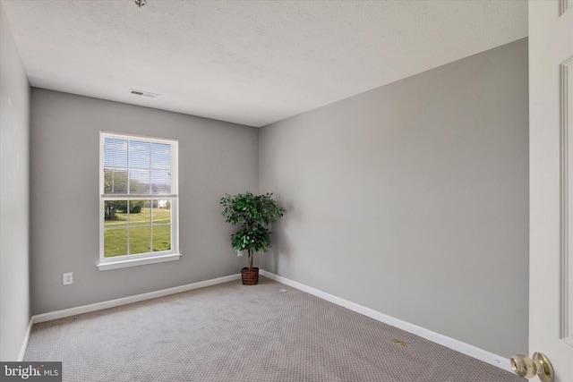 empty room with baseboards, carpet flooring, a textured ceiling, and visible vents