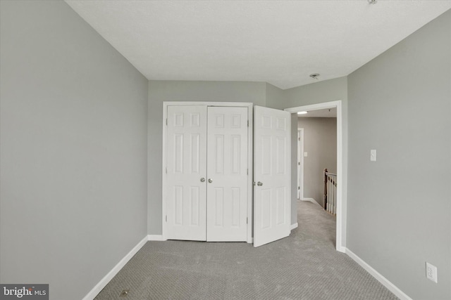 unfurnished bedroom with baseboards, carpet, and a closet