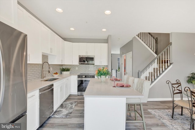 kitchen with a breakfast bar area, a kitchen island, backsplash, appliances with stainless steel finishes, and a sink