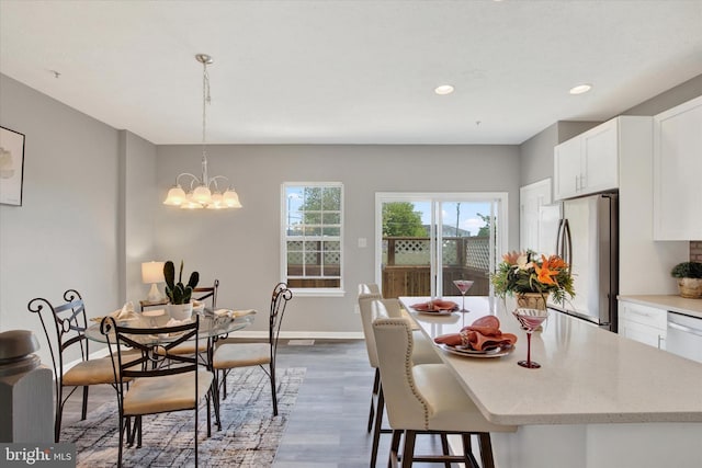 dining area with recessed lighting, baseboards, wood finished floors, and a chandelier