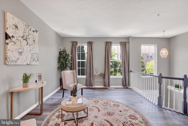 living area with baseboards, a wealth of natural light, and wood finished floors