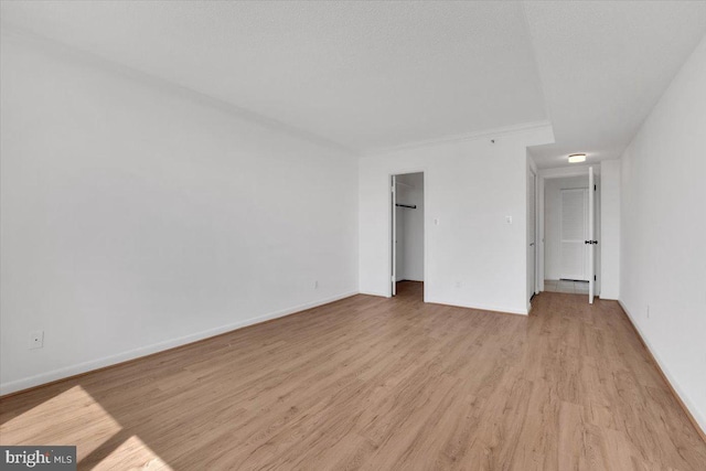 3709 S George Mason Dr Unit 1109E, Falls Church, VA 22041 - unfurnished bedroom with baseboards, a closet, light wood-type flooring, and a walk in closet