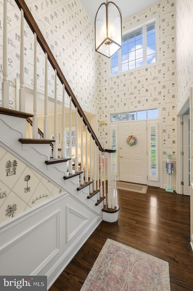 entrance foyer featuring a high ceiling, stairs, wood finished floors, and wallpapered walls