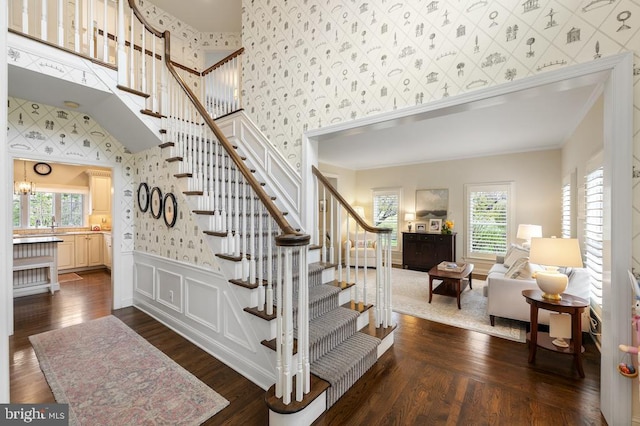stairway featuring crown molding, wallpapered walls, and hardwood / wood-style flooring