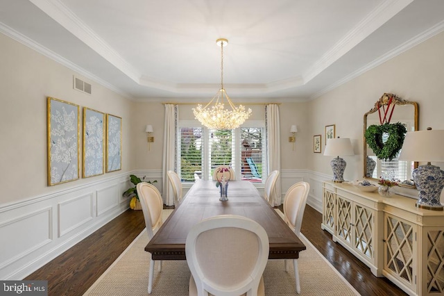 dining area featuring a tray ceiling, a notable chandelier, dark wood-style floors, and visible vents