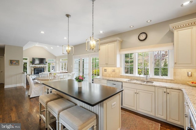 kitchen with cream cabinets, a sink, recessed lighting, open floor plan, and backsplash