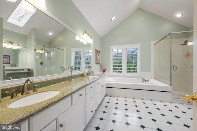 full bath with a sink, vaulted ceiling with skylight, a garden tub, and a stall shower