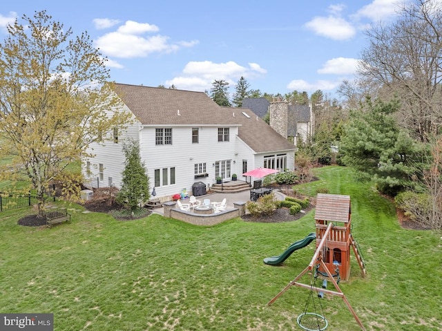 back of property featuring a chimney, a lawn, a playground, a patio, and a shingled roof