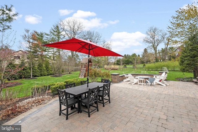 view of patio / terrace featuring a playground, outdoor dining area, and a fire pit