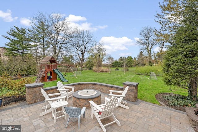 view of patio / terrace featuring fence, a fire pit, and a playground