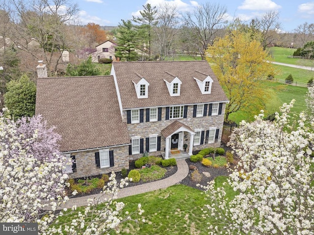 view of front of home with fence, a chimney, a front yard, and stone siding
