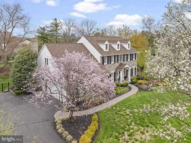view of side of home featuring a lawn, fence, and stone siding