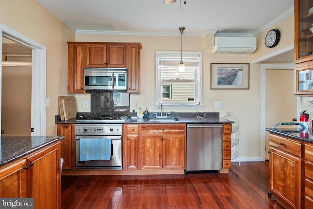 kitchen featuring a sink, an AC wall unit, brown cabinetry, stainless steel appliances, and dark wood-style floors