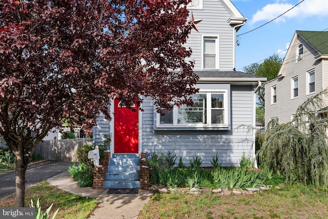 view of front facade featuring fence, a shingled roof, and entry steps