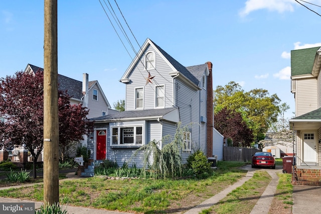 view of front of home featuring fence, driveway, and a chimney