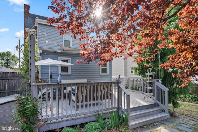 rear view of house with a chimney, fence, and a deck