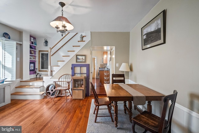 dining space with built in features, wood finished floors, and stairway