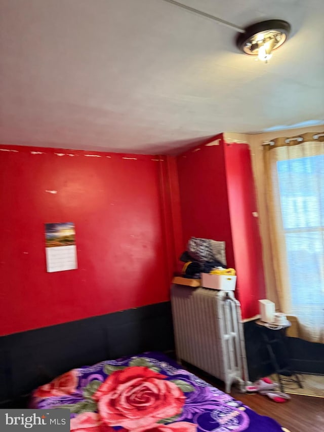 bedroom featuring radiator and wood finished floors