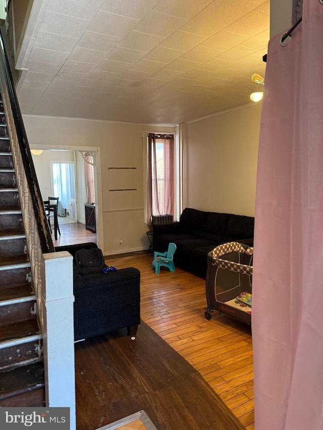 living area with wood-type flooring, a healthy amount of sunlight, and stairway