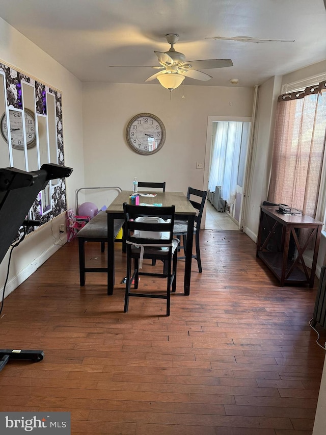 dining room with a healthy amount of sunlight, baseboards, wood-type flooring, and a ceiling fan
