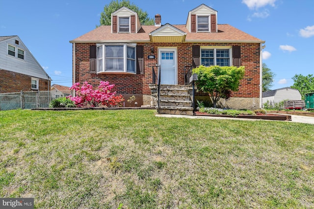cape cod-style house with brick siding, a front lawn, fence, and entry steps