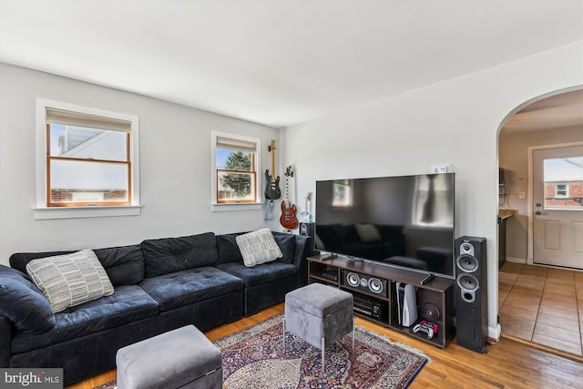 living area with arched walkways and wood finished floors