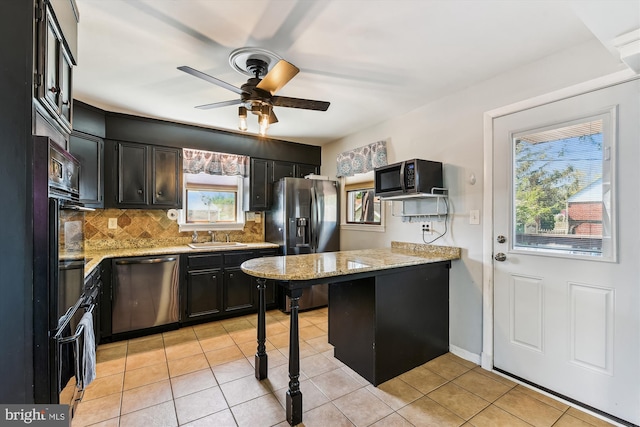 kitchen featuring plenty of natural light, stainless steel appliances, dark cabinets, and a peninsula