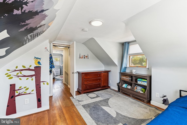 bedroom with baseboards, vaulted ceiling, and hardwood / wood-style floors