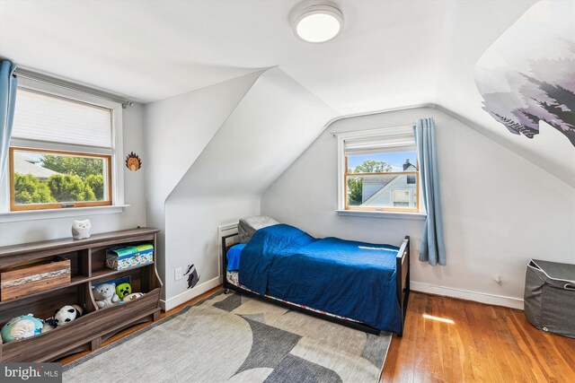bedroom featuring wood-type flooring, baseboards, and lofted ceiling