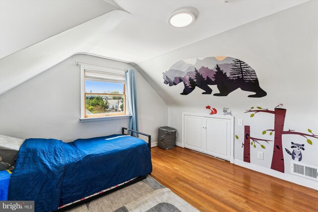 bedroom with baseboards, visible vents, wood finished floors, and vaulted ceiling