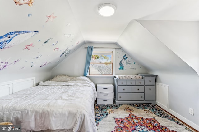 bedroom featuring baseboards, wood finished floors, and lofted ceiling