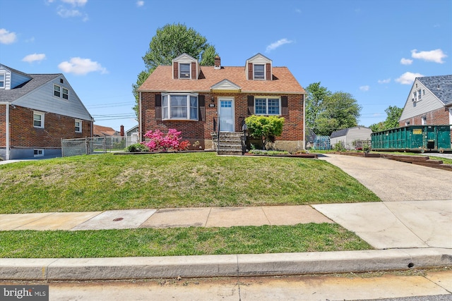 cape cod-style house with brick siding, fence, and a front yard