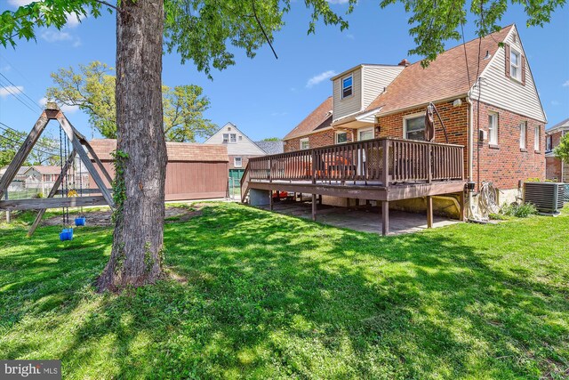 rear view of property featuring central air condition unit, brick siding, a yard, and a wooden deck