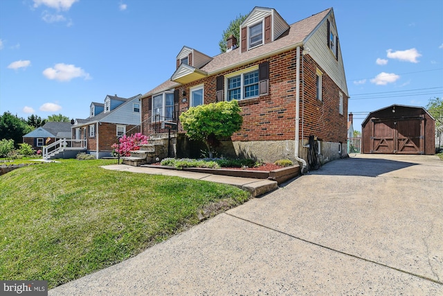 view of front of house with an outdoor structure, a front lawn, brick siding, a storage unit, and concrete driveway