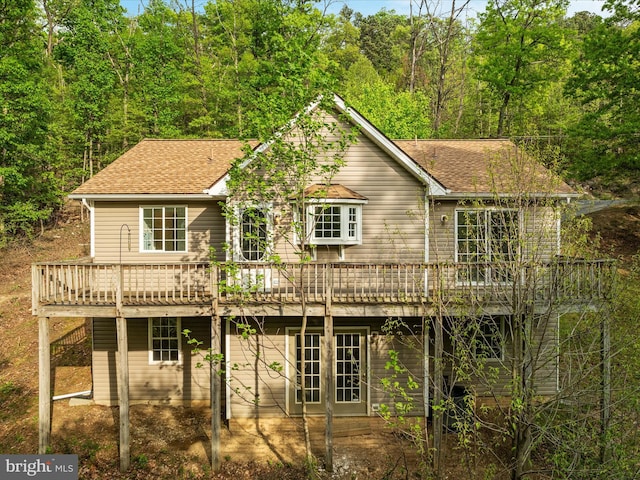 back of house with a wooden deck, a shingled roof, and a patio