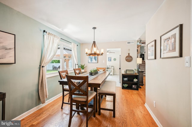dining area with light wood-style floors, baseboards, a chandelier, and a ceiling fan