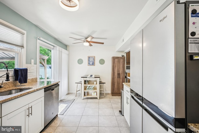 kitchen featuring freestanding refrigerator, a sink, stainless steel dishwasher, ceiling fan, and white cabinetry