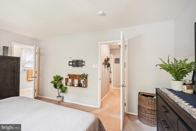 bedroom featuring light carpet, baseboards, and ensuite bathroom