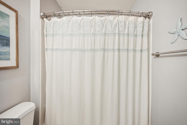 full bath featuring toilet and a shower with curtain