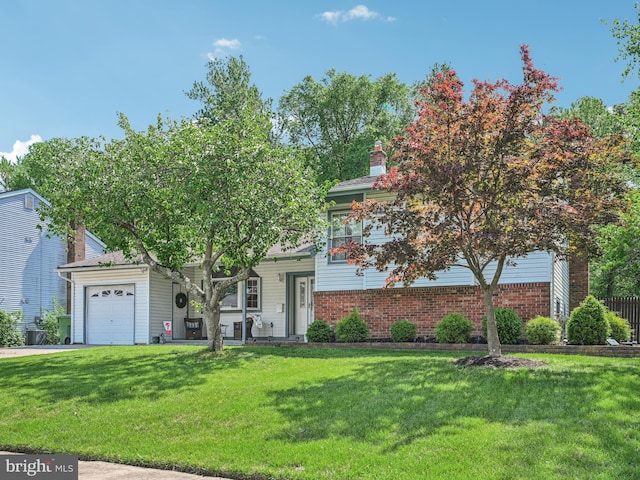 view of front of house featuring an attached garage, a front yard, brick siding, and a chimney