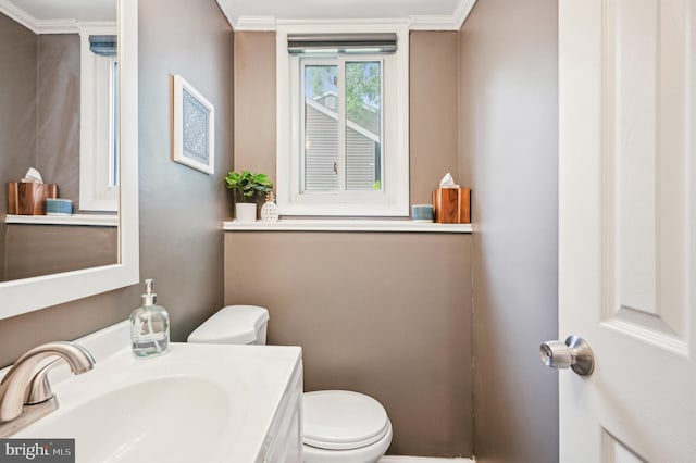 half bathroom featuring toilet, ornamental molding, and vanity